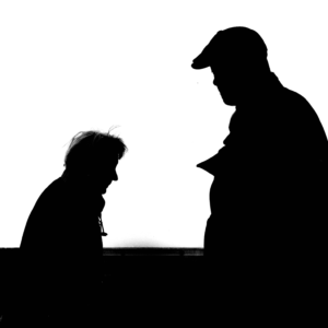 High contrast silhouette photo capturing two adults conversing against a white background.