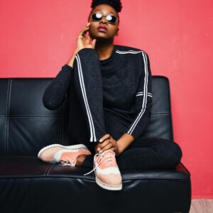 Fashionable woman posing confidently on a sofa in a modern studio setting.